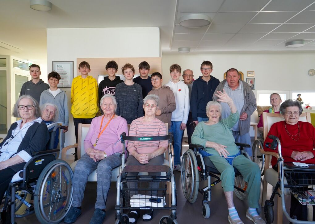 Eine Gruppe von Schülern besucht ein Seniorenheim, um mit den Bewohnern zu interagieren und Zeit zu verbringen.