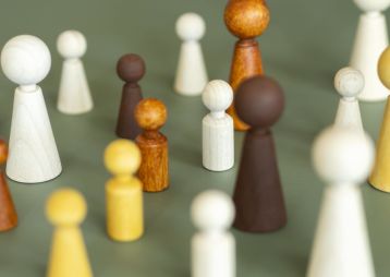 Bunt gefächerte Holzfiguren stehen auf einem grünen Hintergrund, die unterschiedliche Formen und Größen repräsentieren.