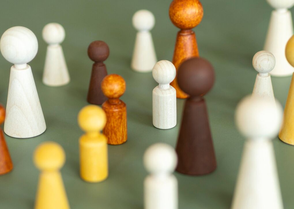 Bunt gefächerte Holzfiguren stehen auf einem grünen Hintergrund, die unterschiedliche Formen und Größen repräsentieren.