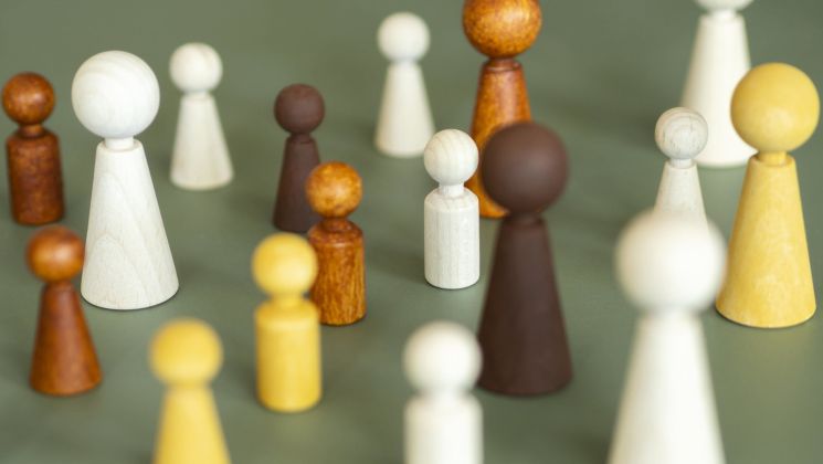 Bunt gefächerte Holzfiguren stehen auf einem grünen Hintergrund, die unterschiedliche Formen und Größen repräsentieren.