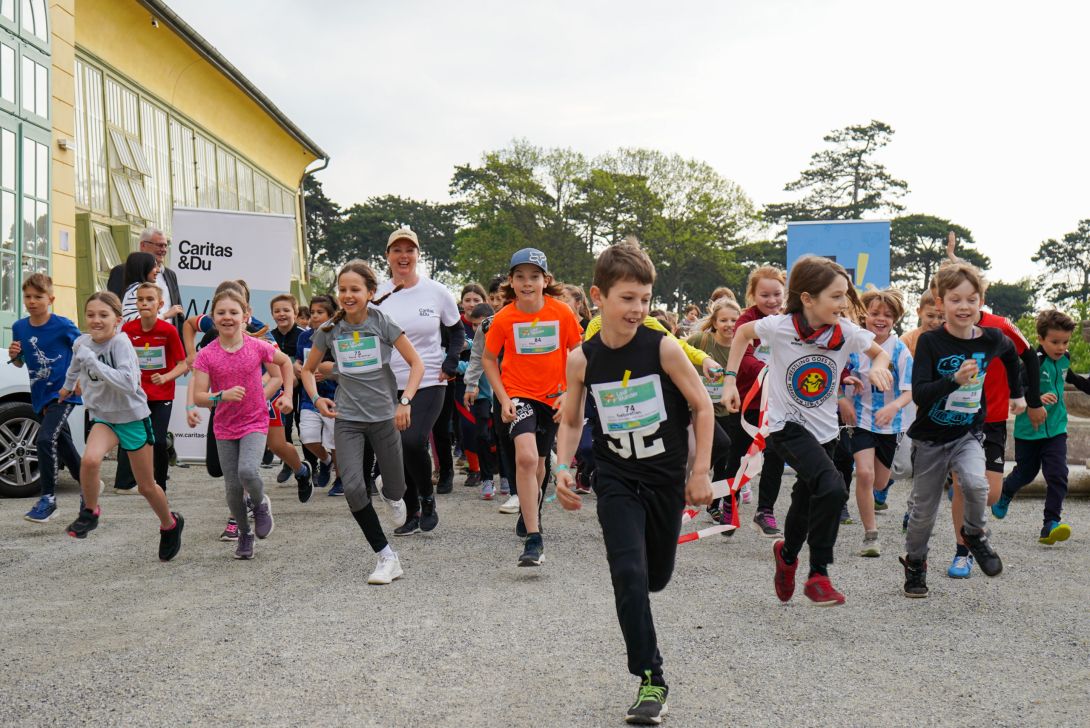 Große Gruppe laufender Kinder beim Start eines Laufwettbewerbs.
