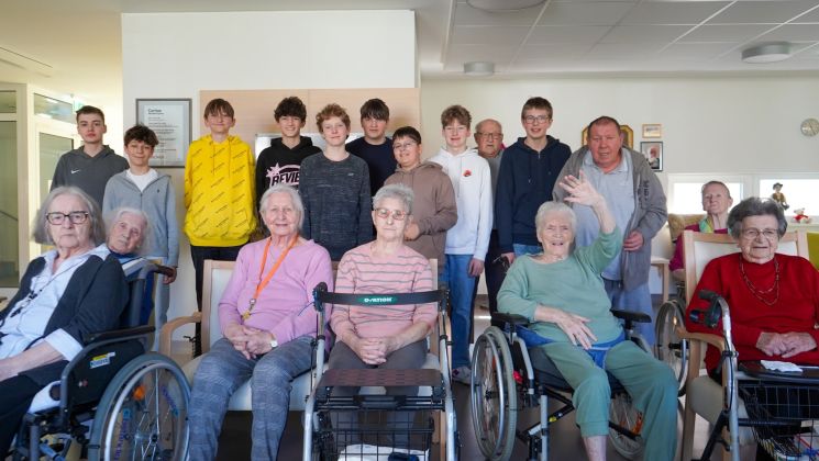 Eine Gruppe von Schülern besucht ein Seniorenheim, um mit den Bewohnern zu interagieren und Zeit zu verbringen.
