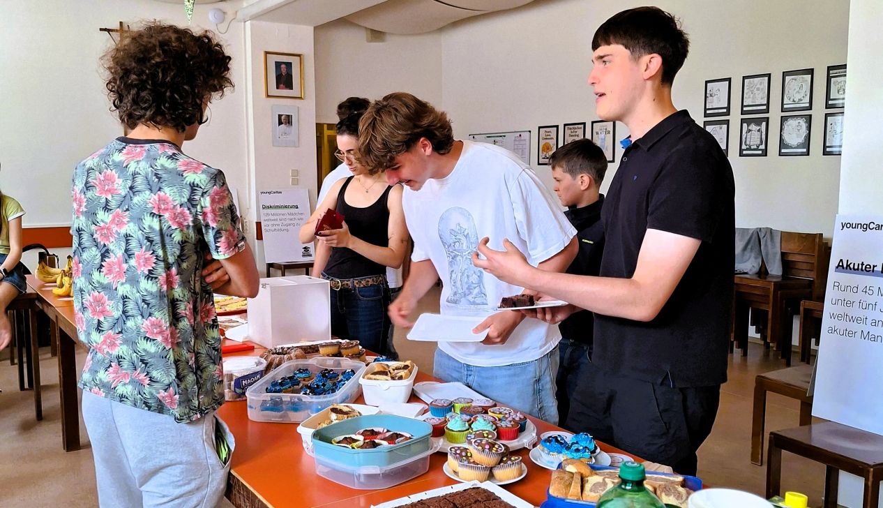 Mehrere Jugendliche stehen an einem Tisch mit Kuchen und bedienen sich.